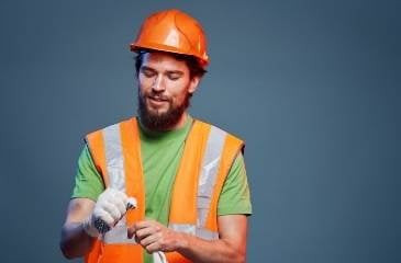 A man in a work uniform is a construction trainee wearing an orange hard hat for white card training course.